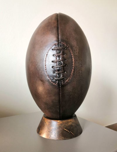 Un ballon de rugby vintage posé sur un socle en bois