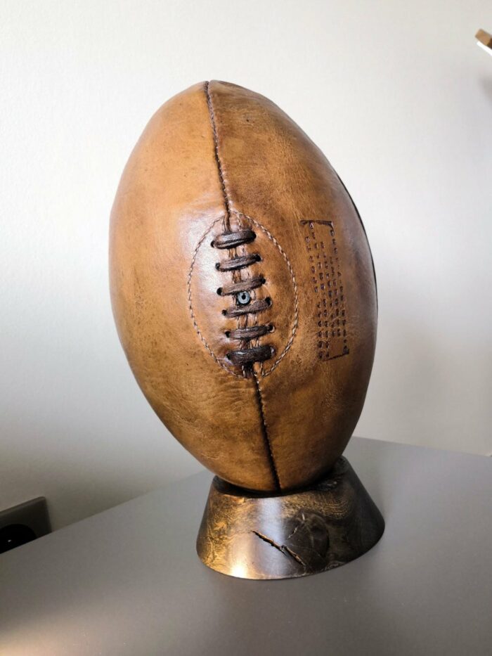 Un ballon de rugby vintage sur un tee en bois