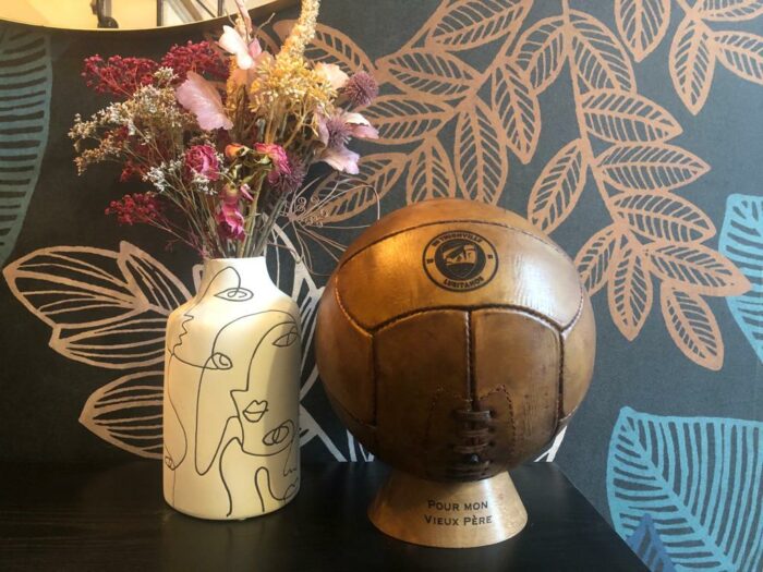 Ballon de foot vintage en cuir exposé sur son socle.