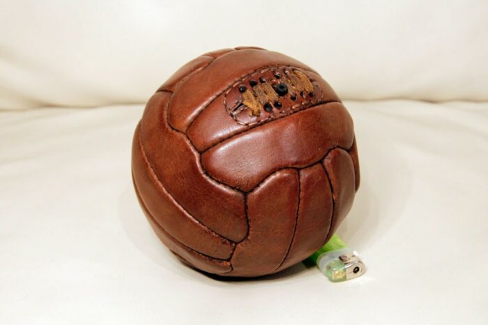 Vintage mini soccer ball placed next to a lighter to see how big it is.