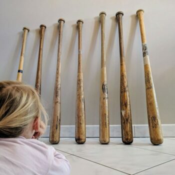 old baseball bats presented on the ground in front of a girl