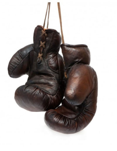 A pair of vintage brown John Woodbridge boxing gloves hung on a white background