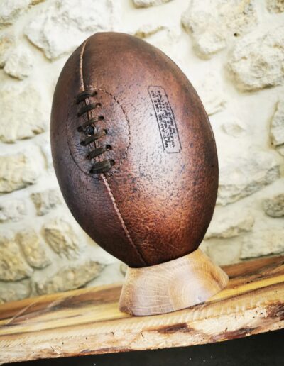 Un magnifique ballon de rugby vintage en cuir brun pour une déco sur un socle