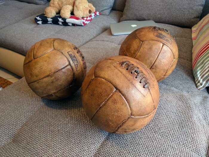 3 antique balls displayed on a sofa