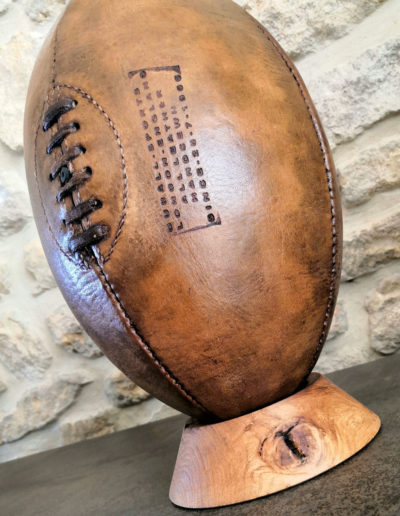 Mise en valeur de la vieille patine d'un vieux ballon de rugby sur son socle en bois