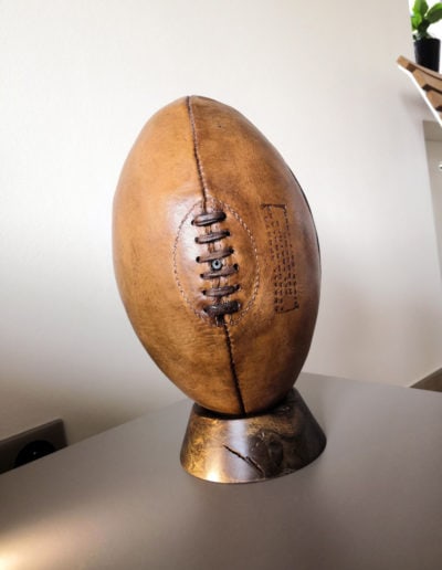 The vintage rugby ball is presented on the dark exotic coloured base