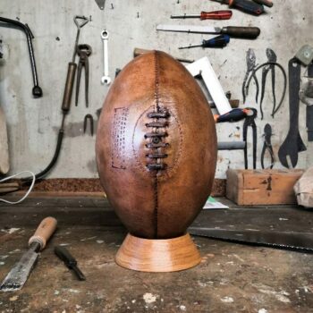 Ancien ballon de rugby présenté dans un atelier avec des outils