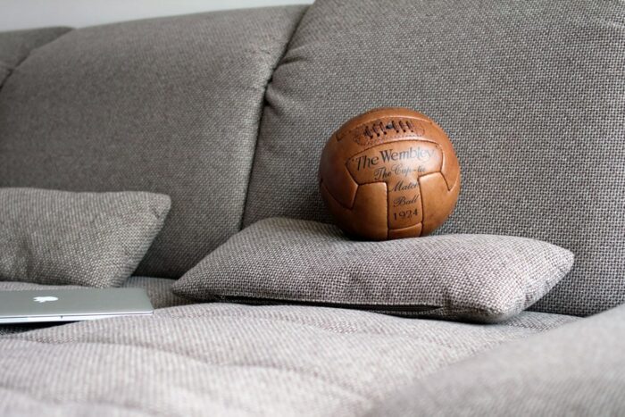 A peaceful pose of an old soccer ball on a sofa cushion