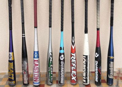 9 antique aluminum baseball bats standing against a wall