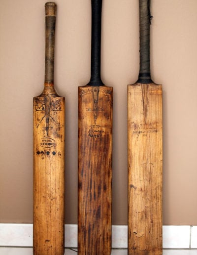 3 old cricket bats against a camel wall in a living room