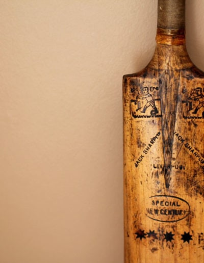 Old cricket bat leaning against a tan wall for decoration