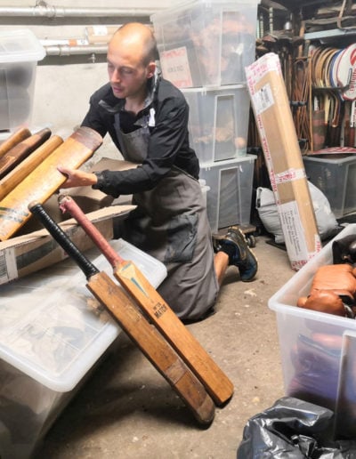 Ben porte un lot de battes de cricket en bois à l'atelier