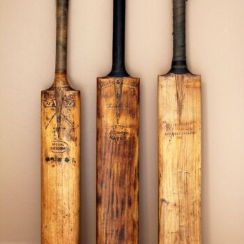 3 old cricket bats against a camel wall