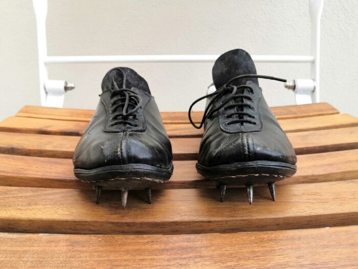 An old pair of athletic spikes on a wooden chair