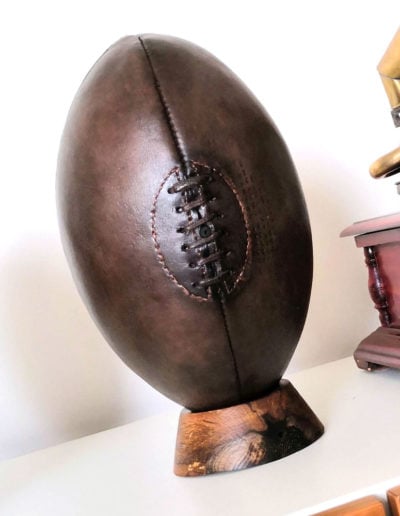 Ancien ballon de rugby en cuir présenté sur un socle rugby (tee)