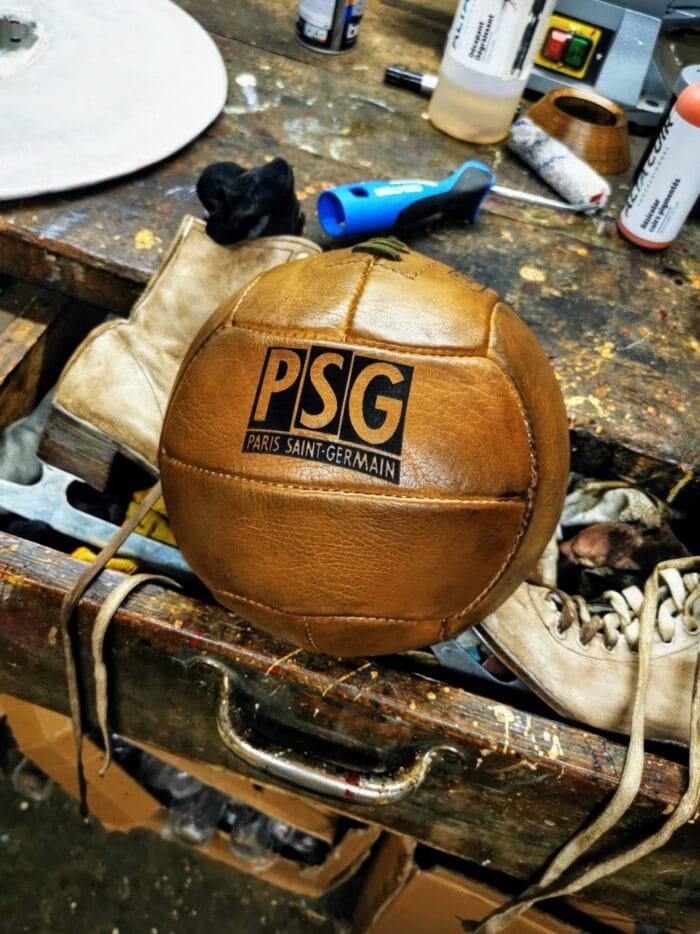 Un ballon de foot vintage du PSG avec le logo gravé sur le cuir aux cleurs miel