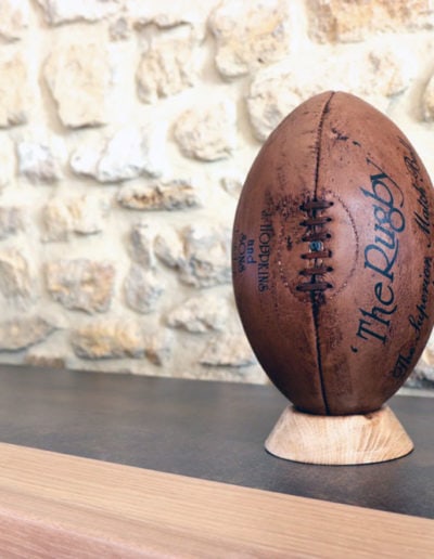 The vintage rugby ball is presented on a clear oak base