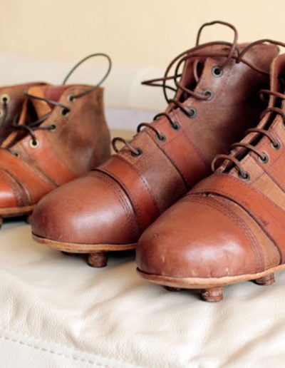 A pair of adult soccer shoes next to an old junior pair