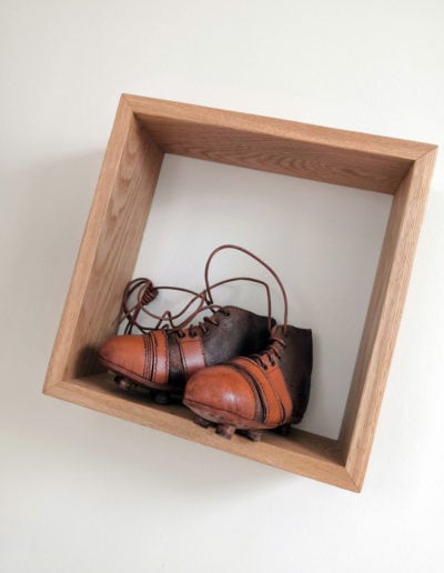 Vintage junior cleats in a wooden cube