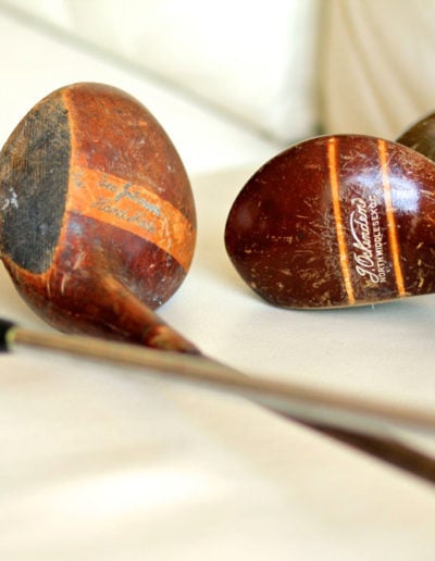 Macro view of the head of an old wooden golf club placed with other clubs