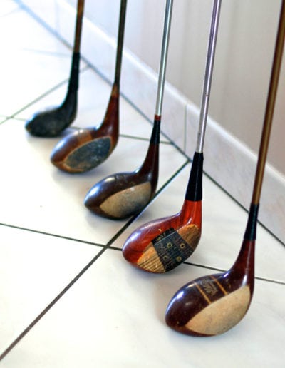 Set of old wood shaft steel golf clubs against a wall