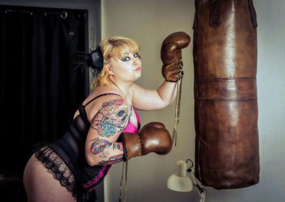 Leather punching bag with a strong, tattooed woman boxing