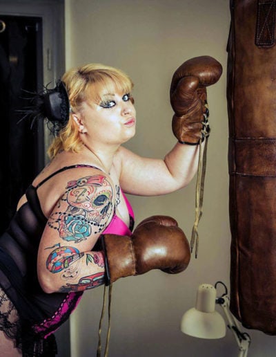 Leather punching bag with a strong, tattooed woman boxing