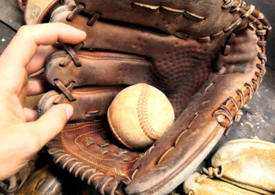 A vintage baseball glove with its ball on a workbench