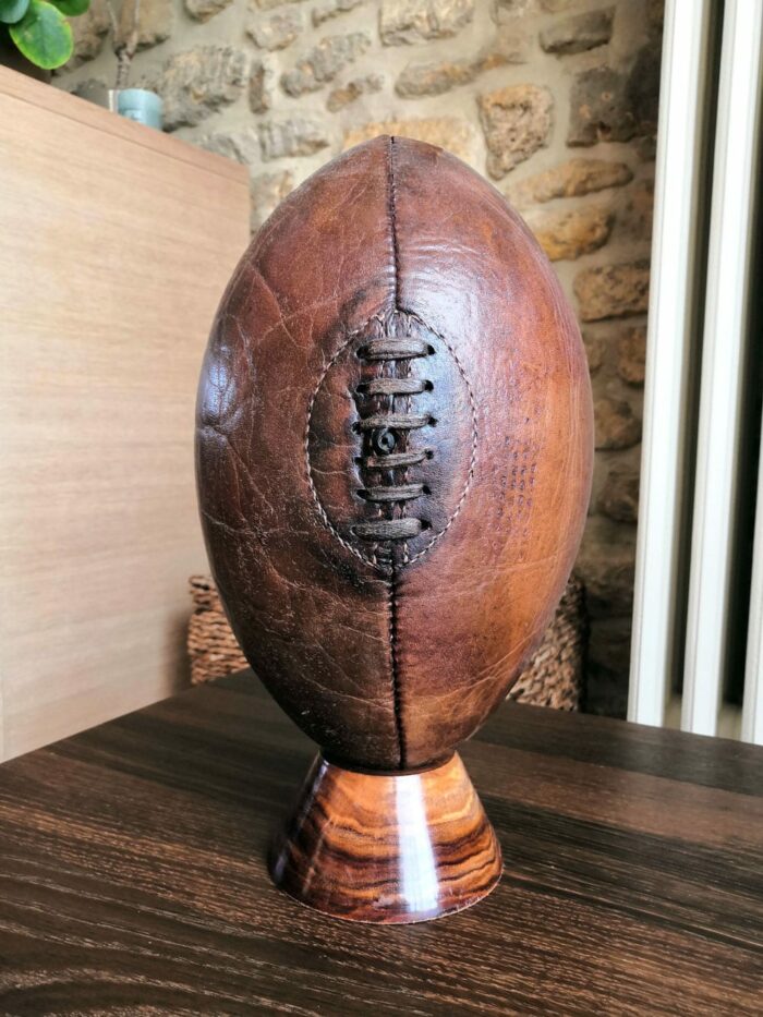 Un ballon de rugby posé sur un tee en bois