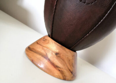 Socle en bois qui supporte un ballon de rugby