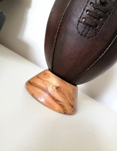 Socle en bois qui supporte un ballon de rugby