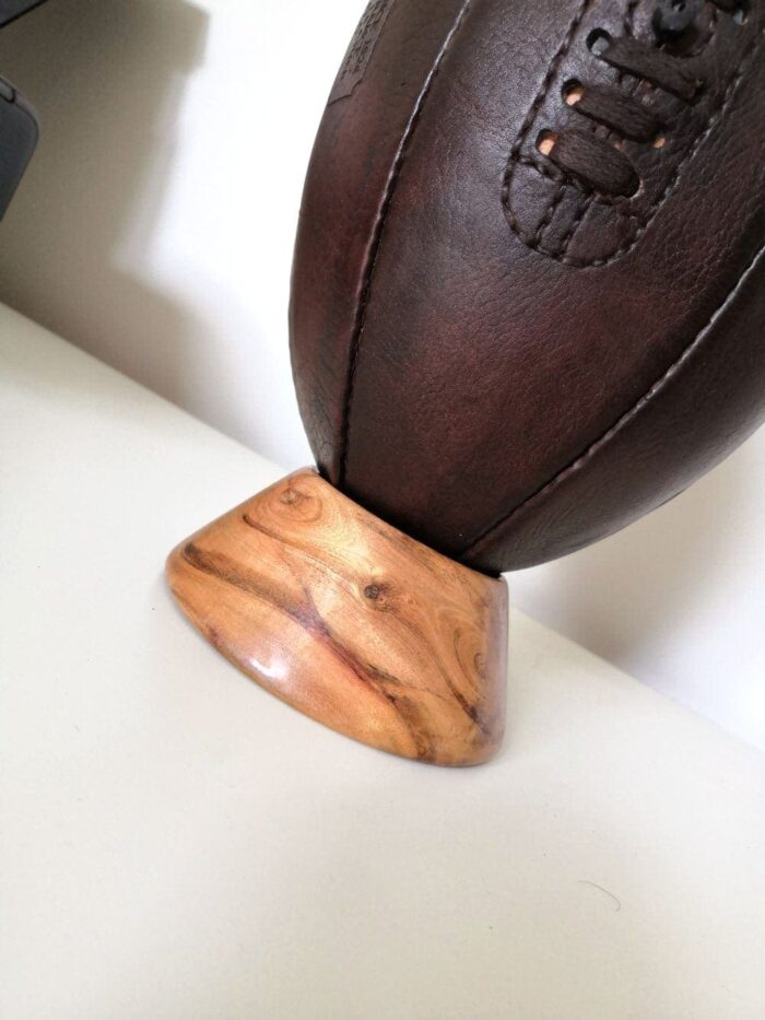 Socle en bois qui supporte un ballon de rugby