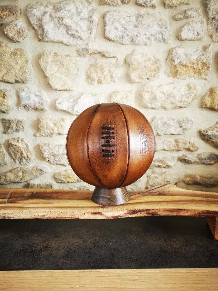 Ballon de basket en cuir vintage couleur miel exposé sur socle en bois massif