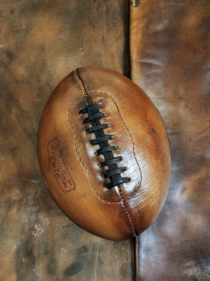 Il s'agit ici d'un ballon de football américain tout en cuir posé sur un autre tapis en cuir de buffle pour se rendre compte de l'ambiance que le ballon peut donner à votre intérieur