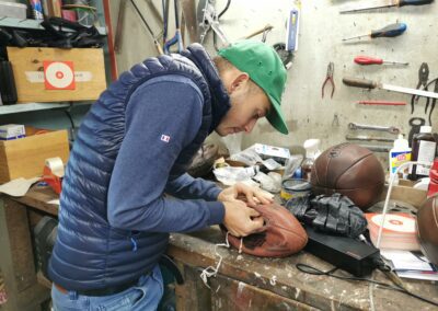 Une personne répare un vieux ballon en cuir dans son atelier.