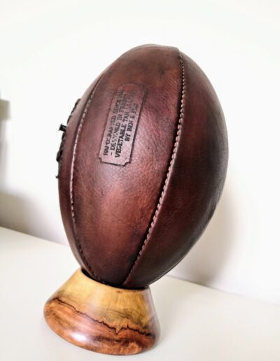 Vue rapprochée de notre ballon de rugby vintage collector en cuir marron sur son socle en bois massif