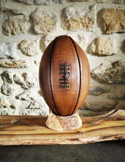 Ballon de rugby rustique posé sur un socle en bois