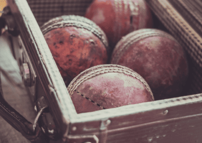 4 balles de cricket vintage présentés dans une petite valise