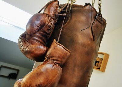 Gants de boxe en cuir accrochés à un sac de frappe également en cuir