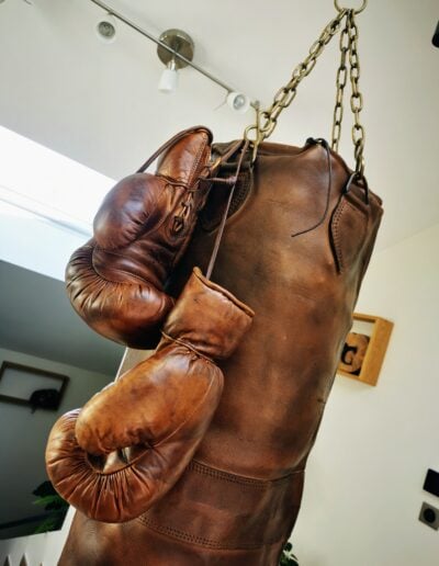 Gants de boxe en cuir accrochés à un sac de frappe également en cuir