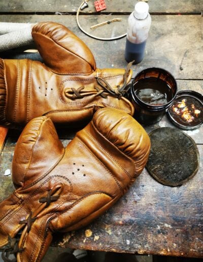 Une paire de gants de boxe en train d'être patiné dans un atelier.