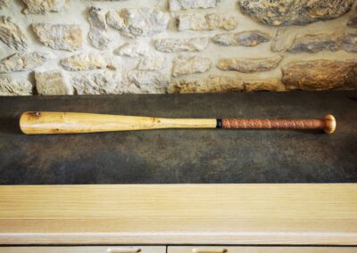 Une batte de baseball en bois vintage posé sur un meuble en guise de décoration