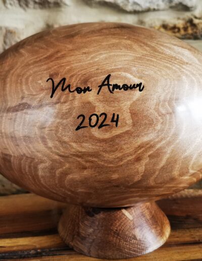 Ballon de rugby en bois, posé sur un socle avec une gravure "mon Amour 2024"