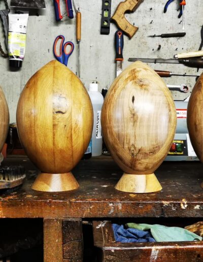 6 ballons de rugby en bois posés sur un atelier