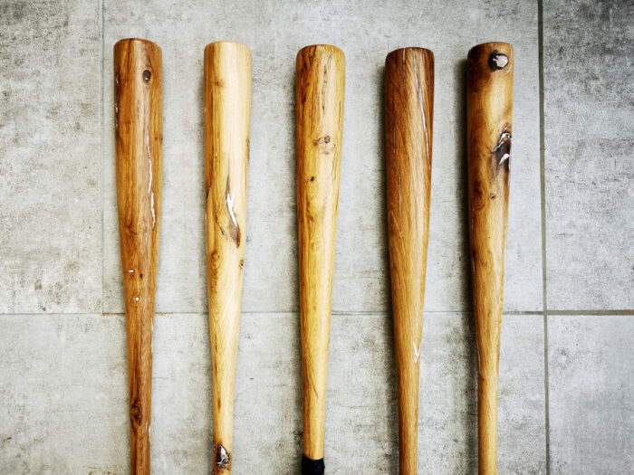 5 battes de baseball en bois vintage posées sur du carrelage gris