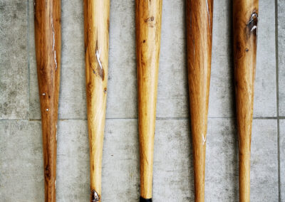 5 battes de baseball en bois massifs posées sur du carrelage