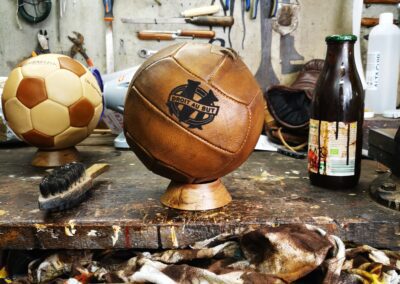 Un magnifique ballon rustique de l'Olympiqe de Marseille posé sur un socle dans un atelier ancien.