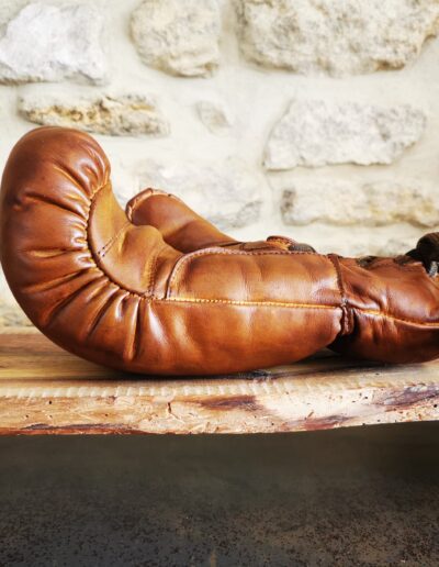 Un gant de boxe en cuir vintage seul posé sur une planche en bois